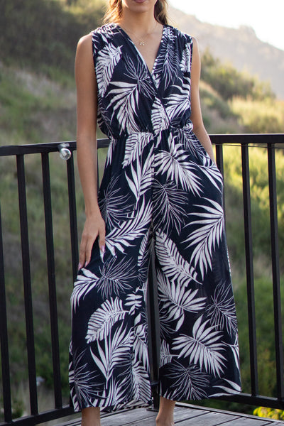 Tropical leaf printed jumpsuit. Has front pockets and adjustable back tie that is sleeveless. Elastic waistband and wide-leg design. Navy colored.