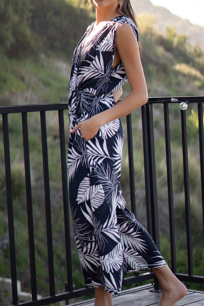 Tropical leaf printed jumpsuit. Has front pockets and adjustable back tie that is sleeveless. Elastic waistband and wide-leg design. Navy colored.