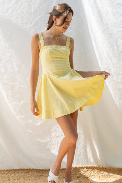 emilia flared mini dress has square neckline and flared silhouette. smocking on the back and adjustable back tie. comes in lemon and white.