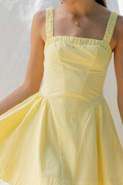 emilia flared mini dress has square neckline and flared silhouette. smocking on the back and adjustable back tie. comes in lemon and white.