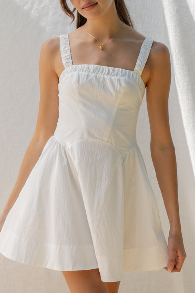 emilia flared mini dress has square neckline and flared silhouette. smocking on the back and adjustable back tie. comes in lemon and white.