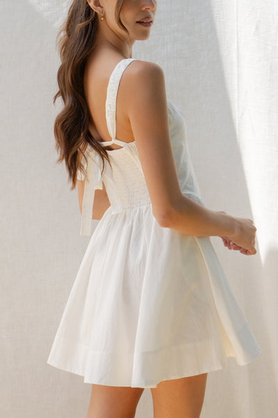 emilia flared mini dress has square neckline and flared silhouette. smocking on the back and adjustable back tie. comes in lemon and white.