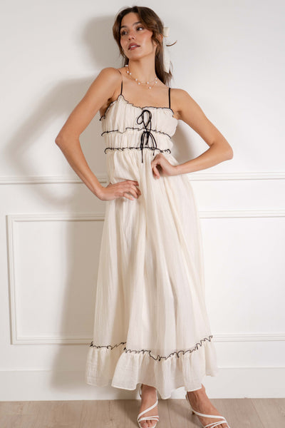 This boho-inspired maxi dress features delicate thin straps, bow tie details, and ruffle accents for a relaxed yet stylish look.
