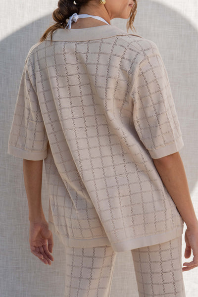 This knit cardigan top features a relaxed fit and short sleeves, perfect for a comfortable and casual look. The square print and buttons along the middle add a touch of style. natural color.