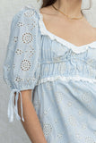Featuring quarter puff sleeves, a playful eyelet design, and charming ruffle details. blue color.