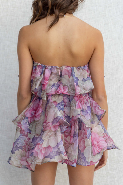 This strapless mini dress features tiered ruffle details and a stunning floral print.