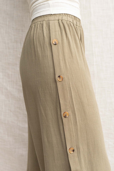 These palazzo bottoms feature a relaxed fit and linen details for a comfortable and stylish look. With an elastic waist band and buttons along the side. olive color.